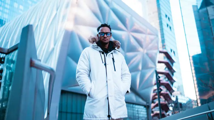 Model in a white parka against a glass building