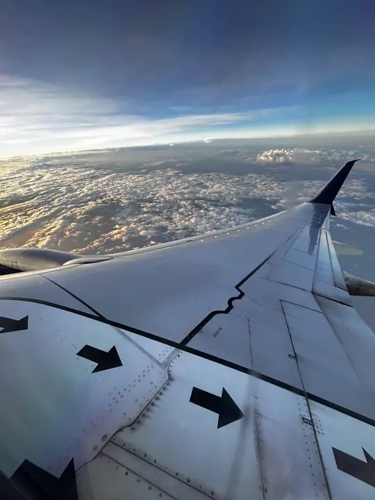 Plane wing over clouds at sunrise