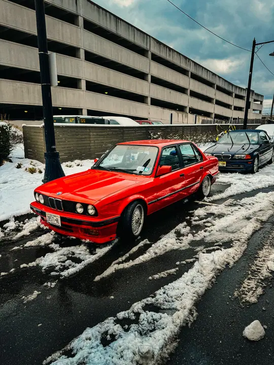 Red BMW in snow beside a parking deck