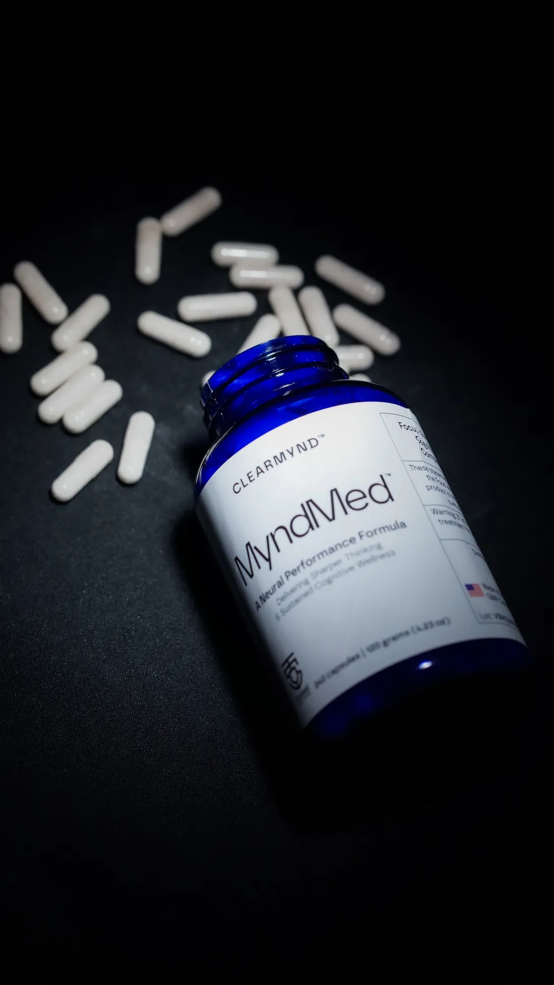 Supplement bottle with capsules scattered on black