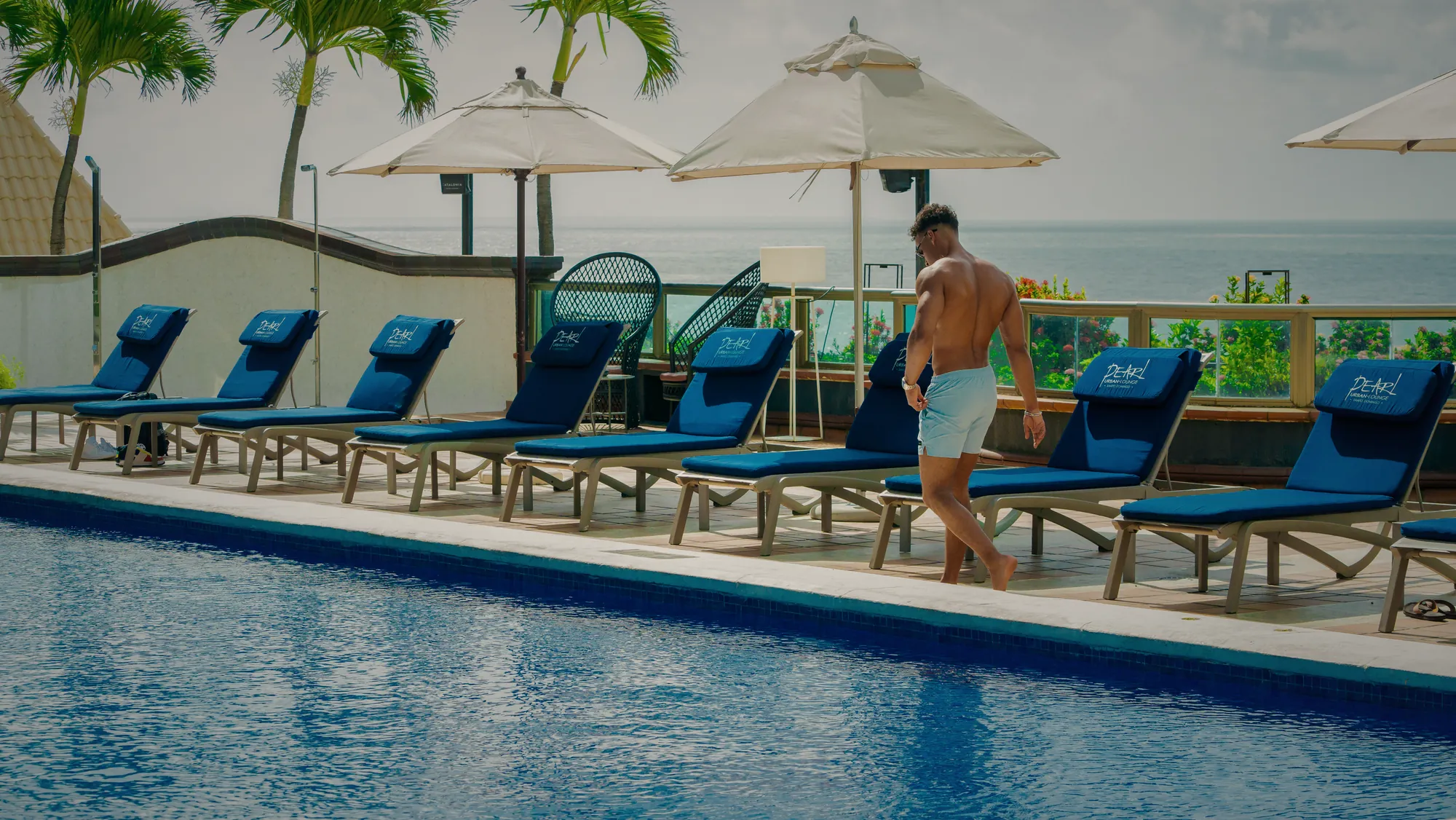 Resort pool deck with branded loungers facing the sea